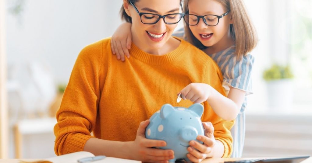 mom and daughter saving money in piggy bank